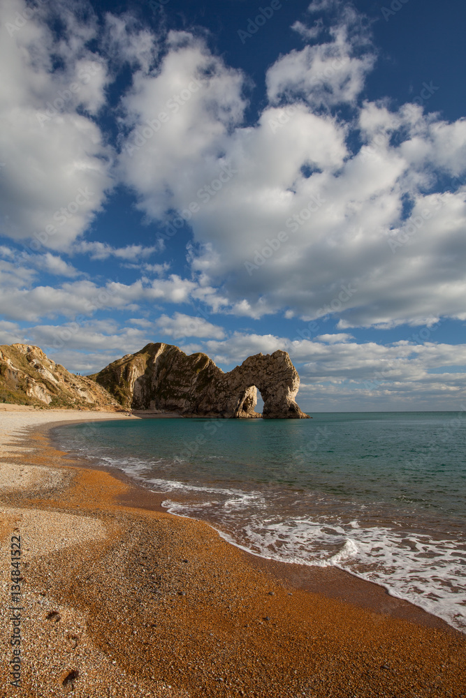 Durdle Door on Jurassic Coast in Dorset, England on sunny day with blue sky and white clouds