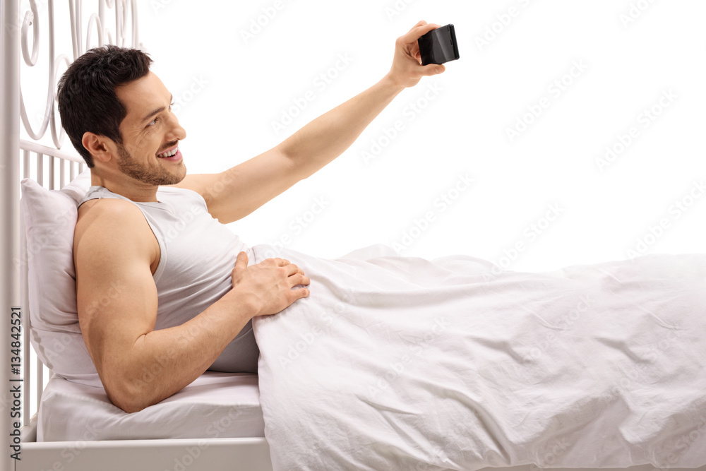 Guy lying in bed and taking a selfie Stock Photo | Adobe Stock