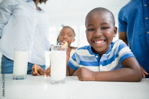 Smiling boy having cookies with milk at home