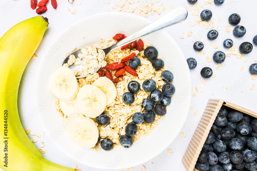 Top View Oat Flakes with Banana Slices, Blueberries and Wolfberries on White Background Top View Oat Flakes with Banana Slices, Blueberries and Wolfberries on White Background
