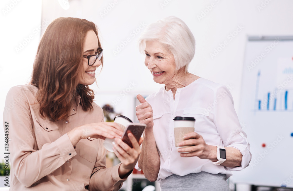 Joyful businesswomen sharing news in the office Joyful businesswomen sharing news in the office