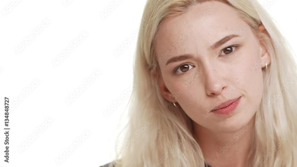 Charming young Caucasian teenage blonde girl grimacing smiling showing tongue on white background in slowmotion. Close up Charming young Caucasian teenage blonde girl grimacing smiling showing tongue on white background in slowmotion. Close up