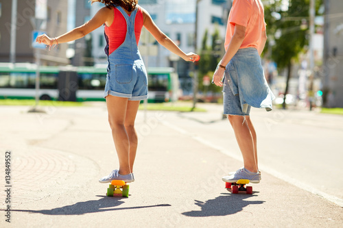 teenage couple riding skateboards on city street