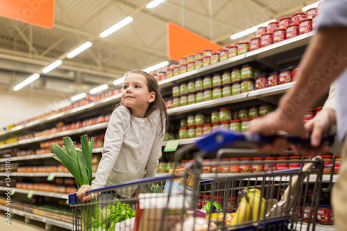 child with father buying food at grocery store photo