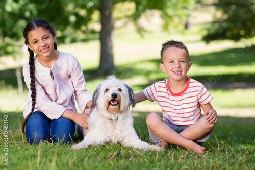 Siblings sitting with their pet dog in park