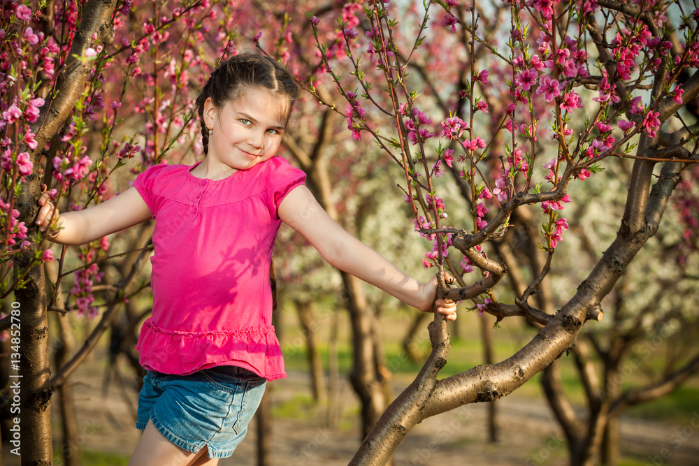 Cute little girl playing on tree in early spring