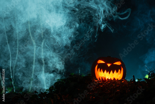 Spooky Gleaming Jack-o-Lantern in Dark, Smoky Setting with Copy