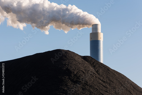Photo Pile of coal with the chimney of a coal power plant behind