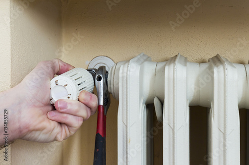 Plumber at work installing a thermostatic valve on a radiator