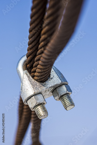 Rusty Steel Ropes with Shiny U-Bolt Clamp on Blue Sky Background. Business Teamwork Support Together Concept.