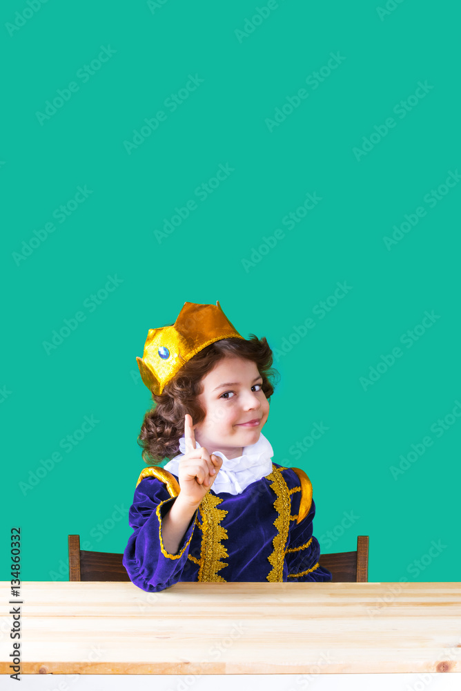 Young handsome prince faces an index finger, smiling, looking into the camera. Close-up. Turquoise background. Young handsome prince faces an index finger, smiling, looking into the camera. Close-up. Turquoise background.
