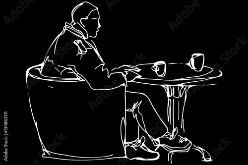 man at the round table in a cafe drinking coffee