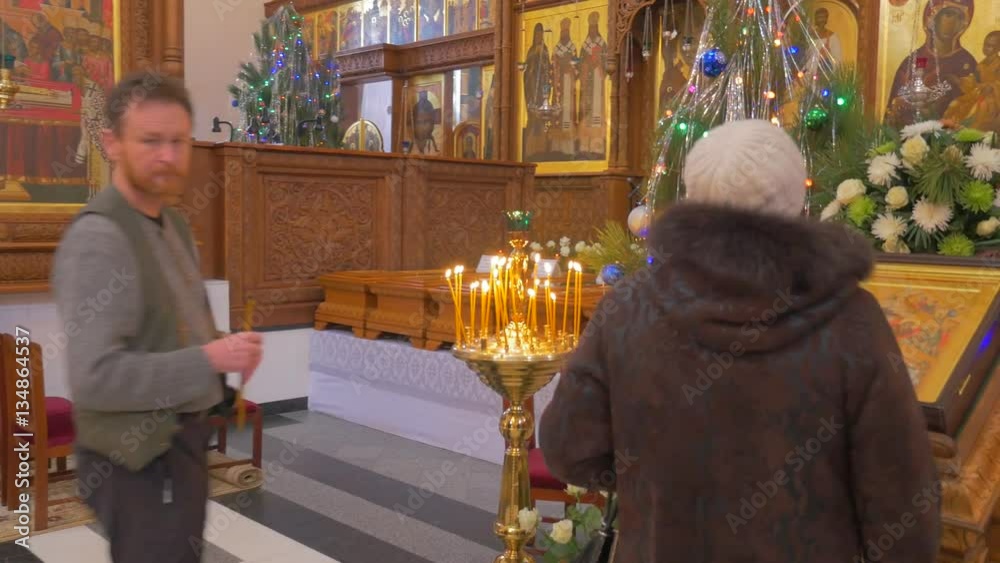 a Man and a Woman Pray Before an Iconostasis, Which Looks Majestic With Its Golden Looking Icons, Images of Saints, Decorated Fir Trees and so on a Man and a Woman Pray Before an Iconostasis, Which Looks Majestic With Its Golden Looking Icons, Images of Saints, Decorated Fir Trees and so on