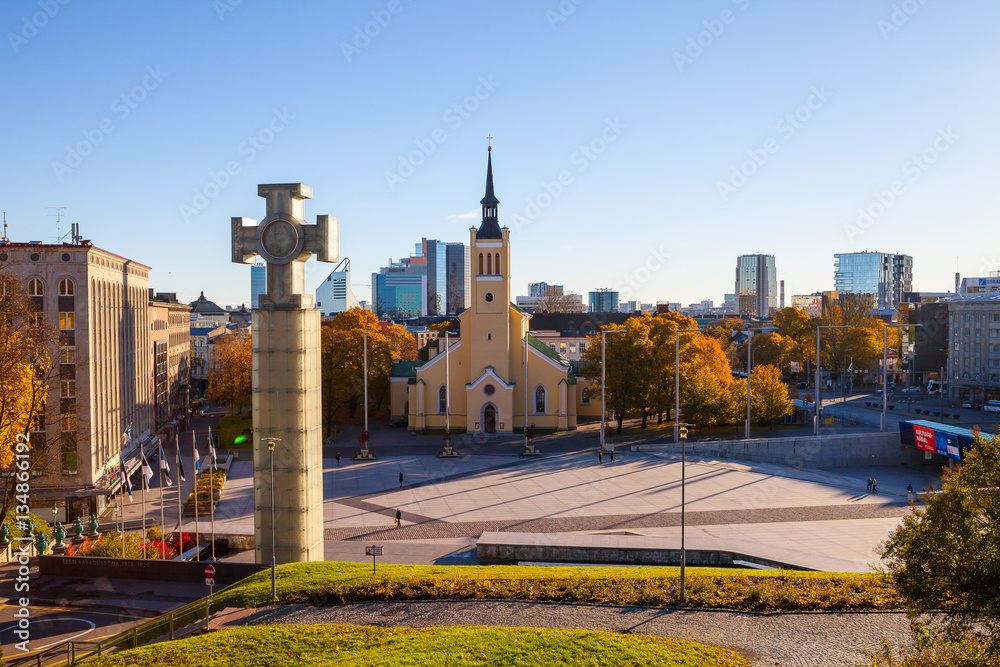 Sunny summer view of Freedom Square, Estonian cross and St. John Church