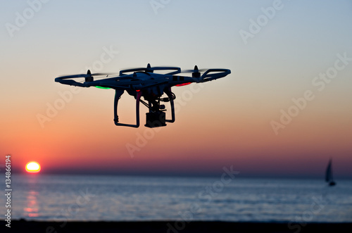 Flying drone with camera on the sky at sunset © jon11