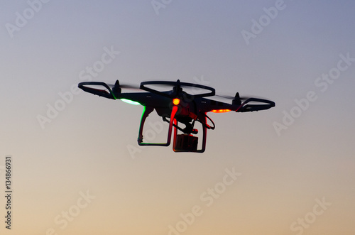 Flying drone with camera on the sky at sunset