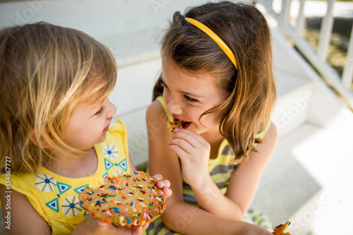 Two young girls sharing a cookie, close up  photo