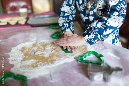 Childs hands making cookies with festive cutters 