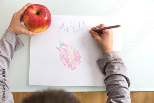 Hands of child drawing and writing apple  photo
