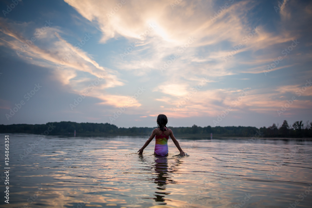 Rear view of girl walking in lake at sunset Rear view of girl walking in lake at sunset