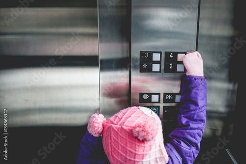 Young girl pressing elevator button 