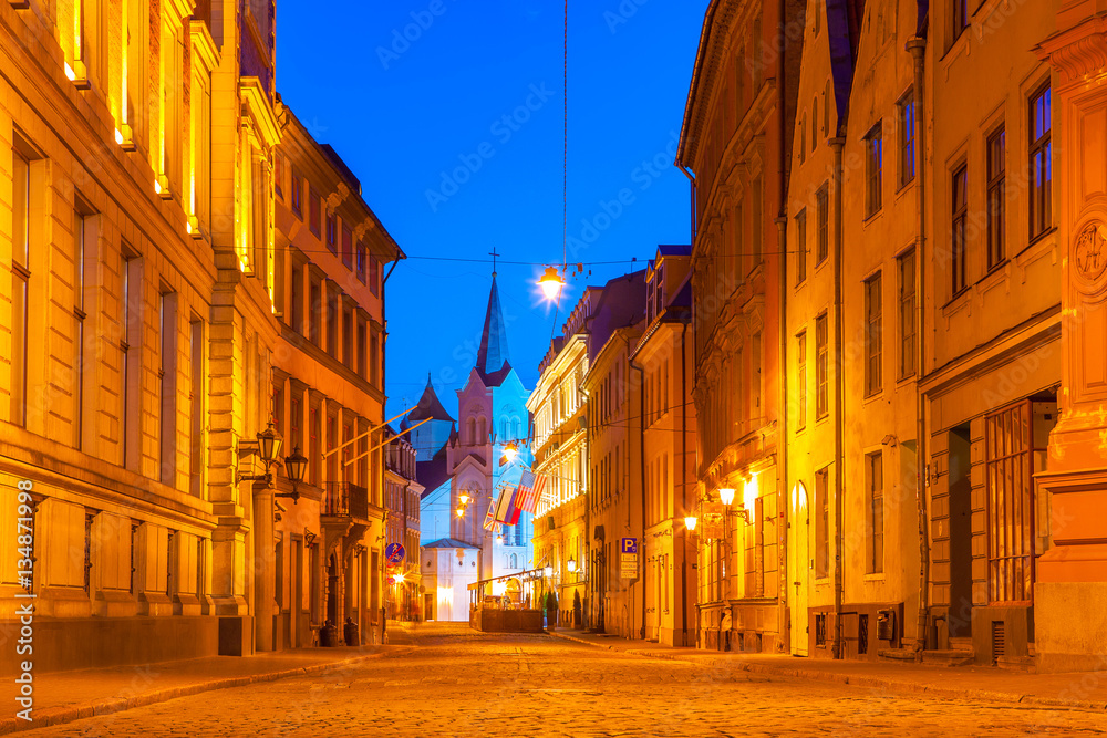 Illuminated street in old part of Riga by night. The Our Lady of Sorrows Church.
