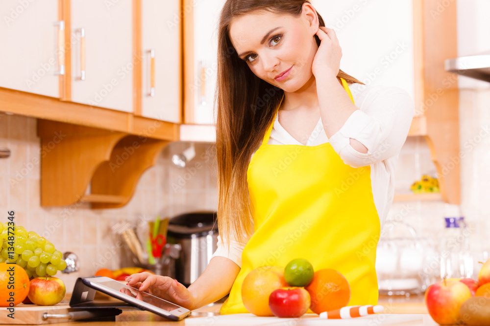 Woman housewife in kitchen using tablet