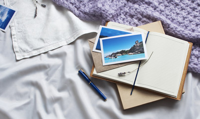 Notebook letter and book travel photographs on a white textile in bed. Diary Envelope Lifestyle Plaid Scarf Lavender