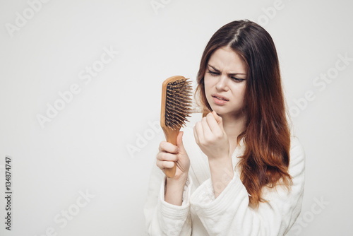 woman with long hair looks at comb