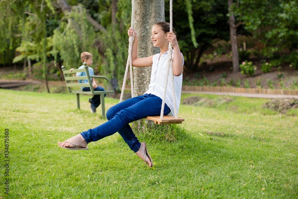Obraz premium Happy girl sitting on a swing in park