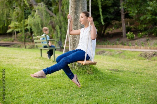 Happy girl sitting on a swing in park