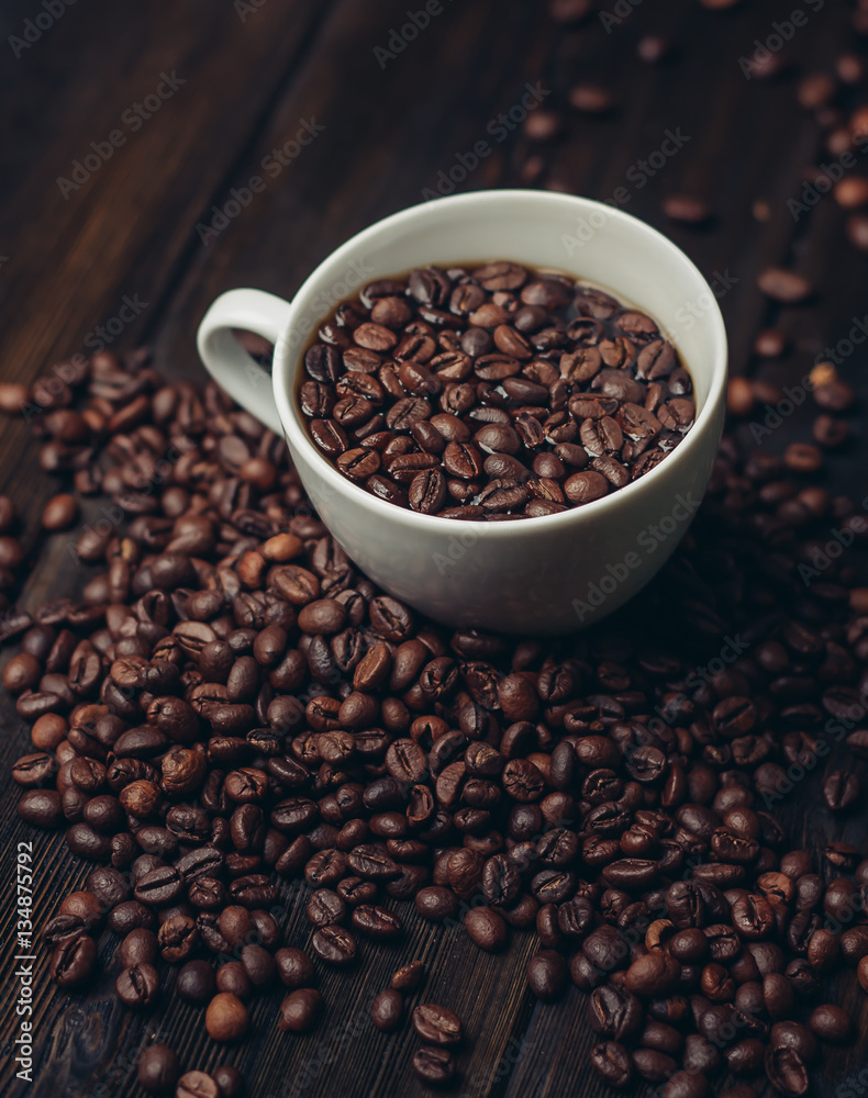 coffee beans in a mug and on a table coffee beans in a mug and on a table