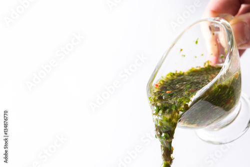 Pouring chimichurri sauce on white background. Copyspace.
 photo