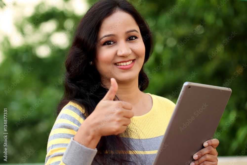 Fototapeta premium Happy young woman holding tablet computer at outdoor