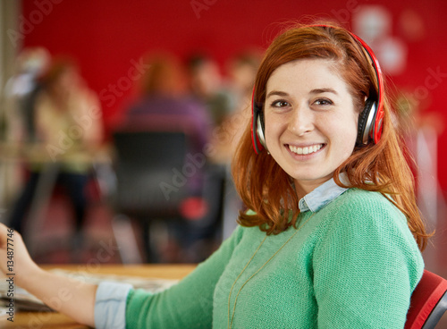 Confident male designer listening to music in red creative office space
