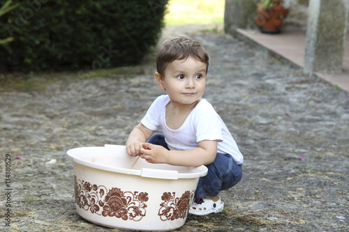 little kid playing with water in a plastic tub