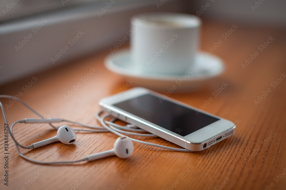 Smartphone, headphones and coffee cup on wooden table Smartphone, headphones and coffee cup on wooden table