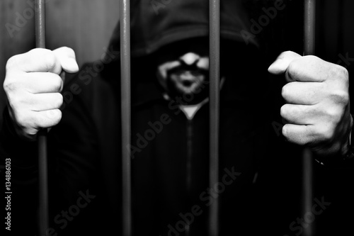 Abstract. Hands of the prisoner on a steel lattice close up. Prison, man in handcuffs. photo