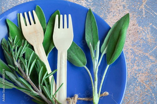 Green fresh italian herbs - rosemary and salvia leaves on blue plate. Top view.