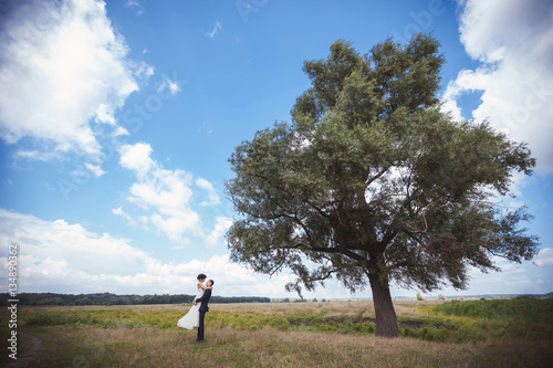 Bride and groom hugging near tree © Wedding photography