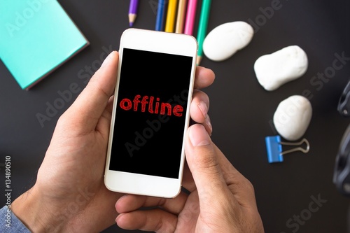 Offline, text message on screen at hands take smartphone, black table with office supplies backdrop background . business concept.