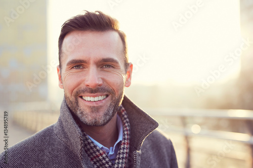 Portrait of happy man smiling outdoors during cold winter day