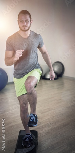 Portrait of serious man doing exercise on aerobic stepper 