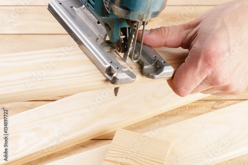 man carpenter builder working with electric jigsaw and wood