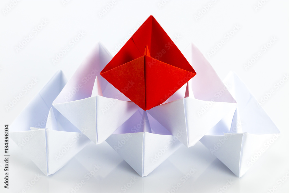 Leadership concept with red paper ship leading among white Leadership concept with red paper ship leading among white