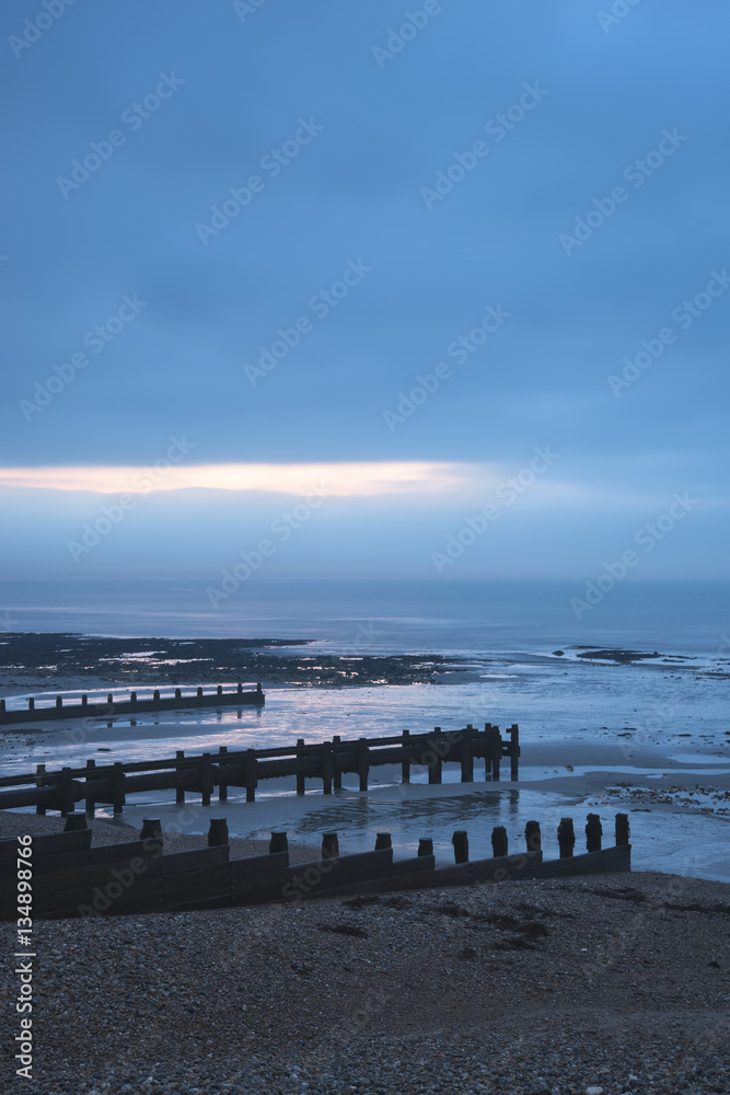 Cold Winter beach sunrise landscape at low tide with dramatic sk