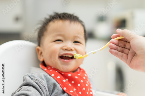 Asian baby boy eating blend food on a high chair