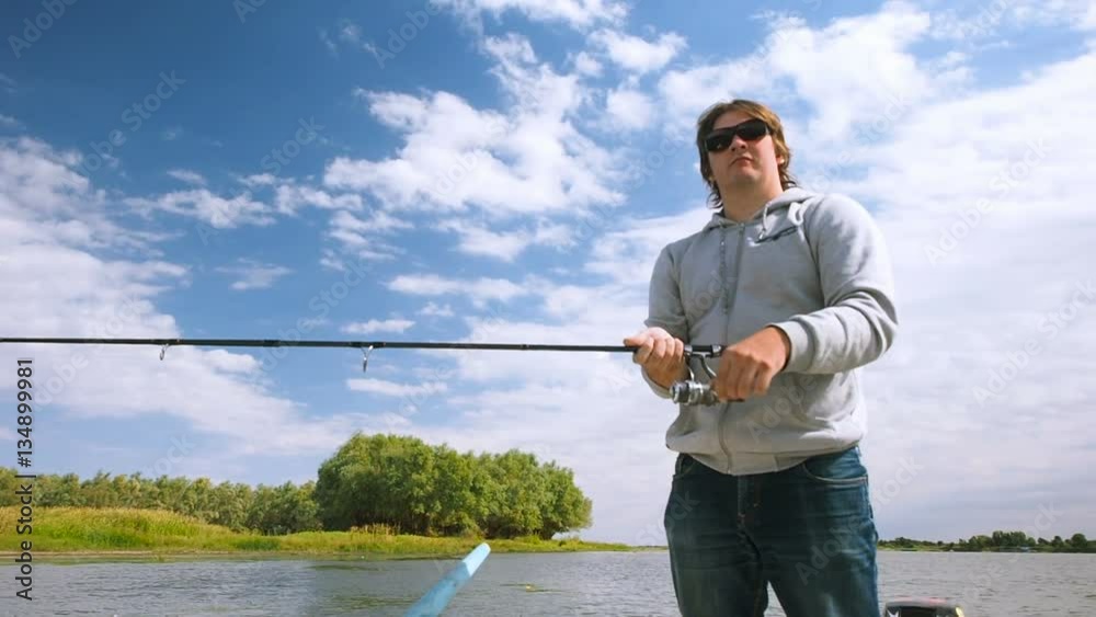 Fisherman catches a fish from a motor boat on the river. Man on the boat fishing on the rod or spinners in the Volga delta Fisherman catches a fish from a motor boat on the river. Man on the boat fishing on the rod or spinners in the Volga delta