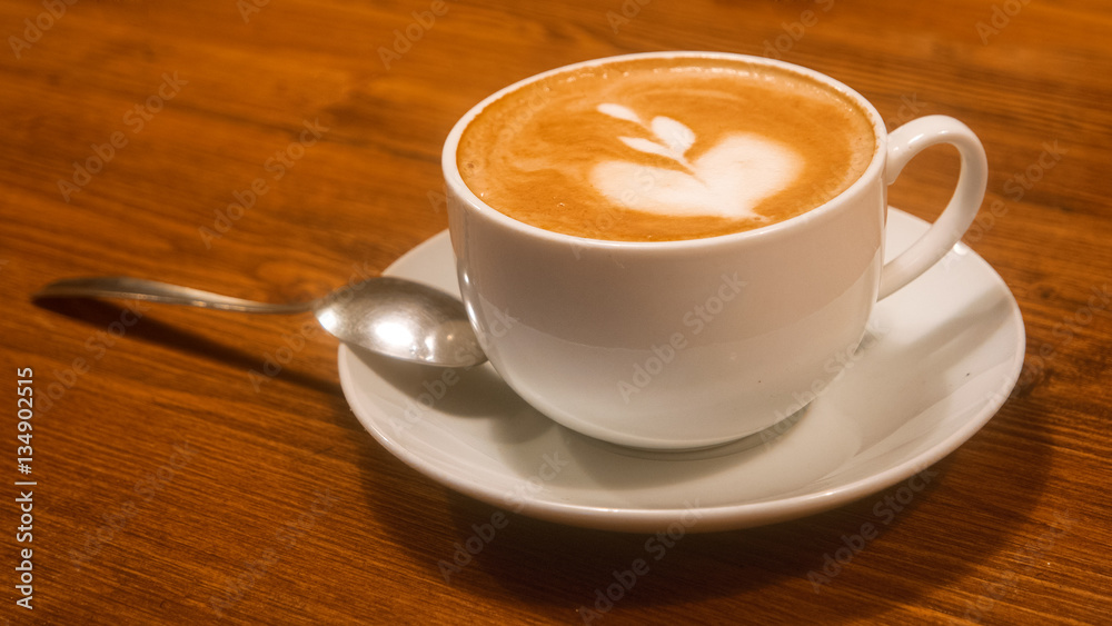 Hot cappuchino coffee cup on brown wooden table angle cloeup view Hot cappuchino coffee cup on brown wooden table angle cloeup view