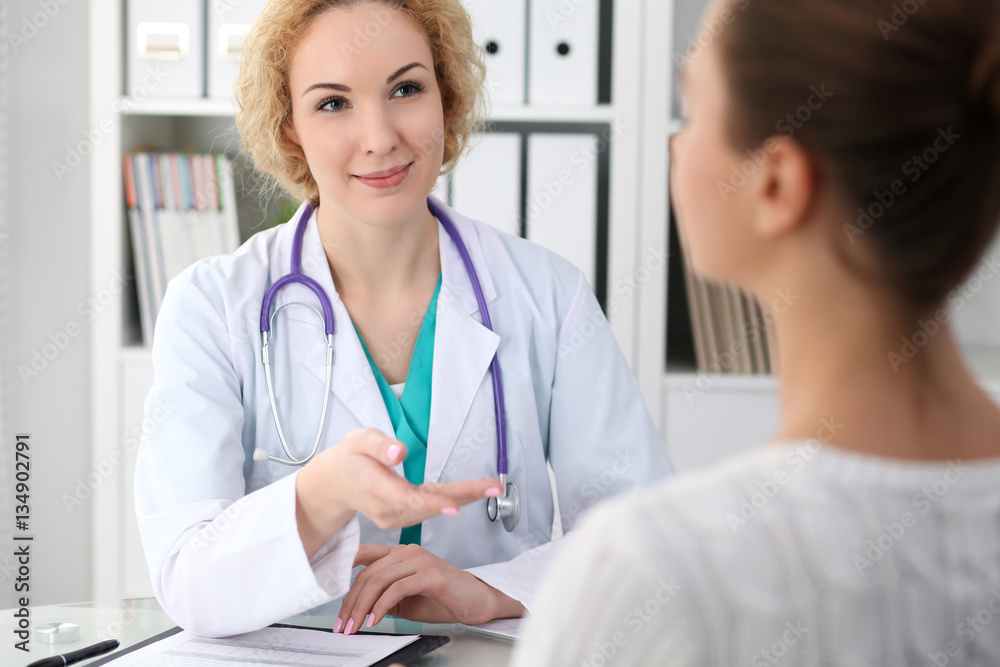 Happy blonde female doctor and patient discussing medical examination results. Medicine, healthcare and help concept Happy blonde female doctor and patient discussing medical examination results. Medicine, healthcare and help concept